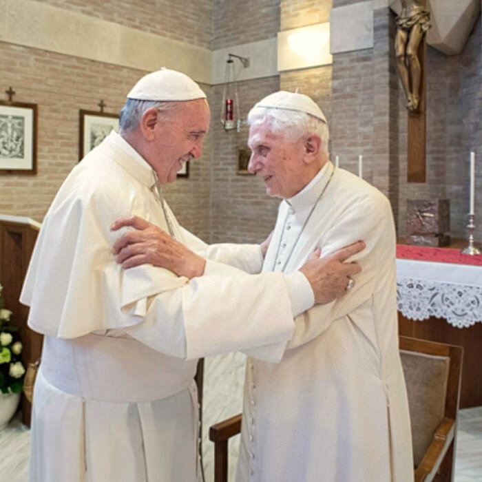 Papst Franziskus und der emeritierte Papst Benedikt begrüßen sich mit offenen Armen.
